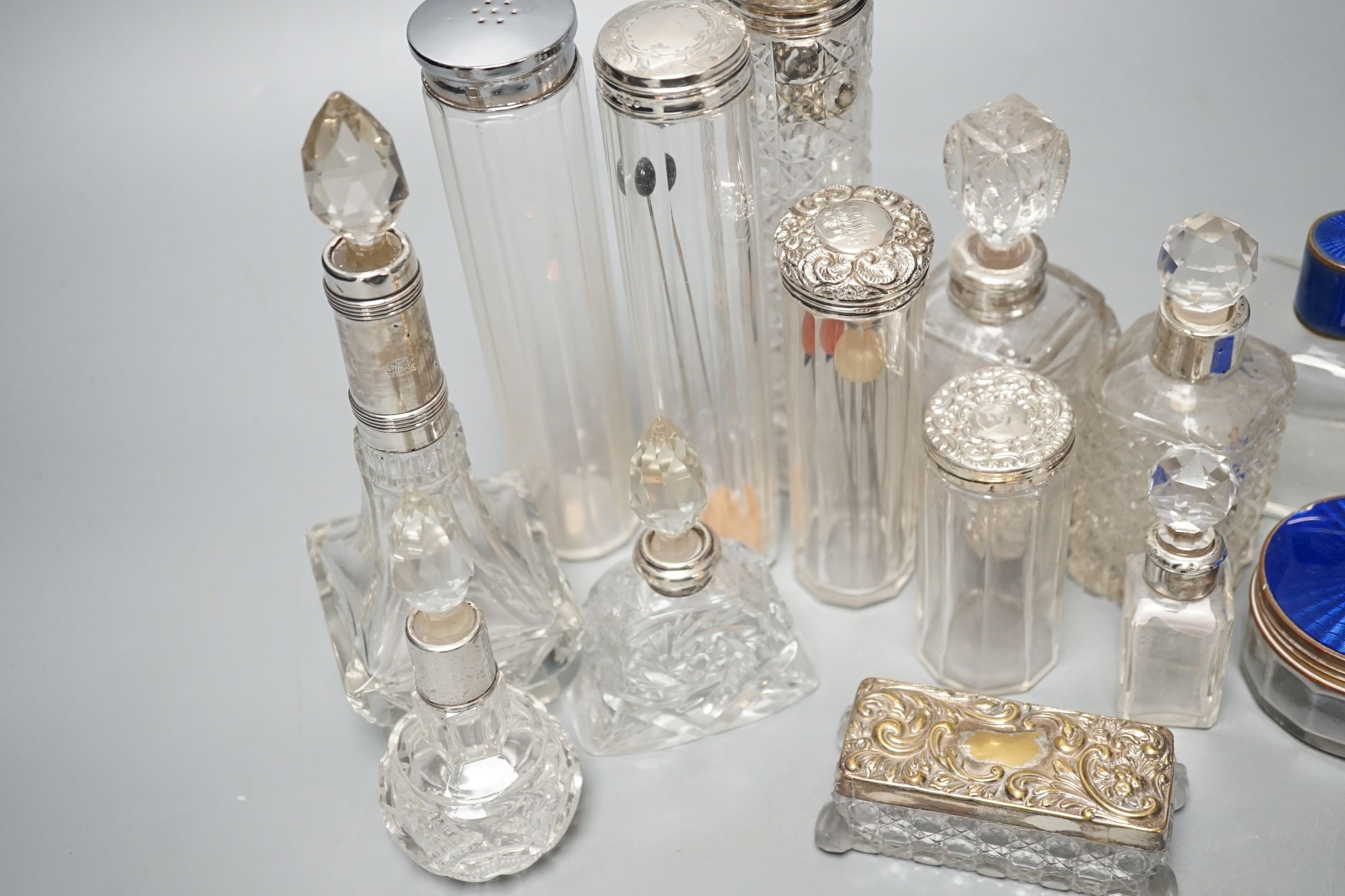 A collection of assorted mainly silver-capped scent bottles and toilet jars, etc. including two gilt metal and enamel.